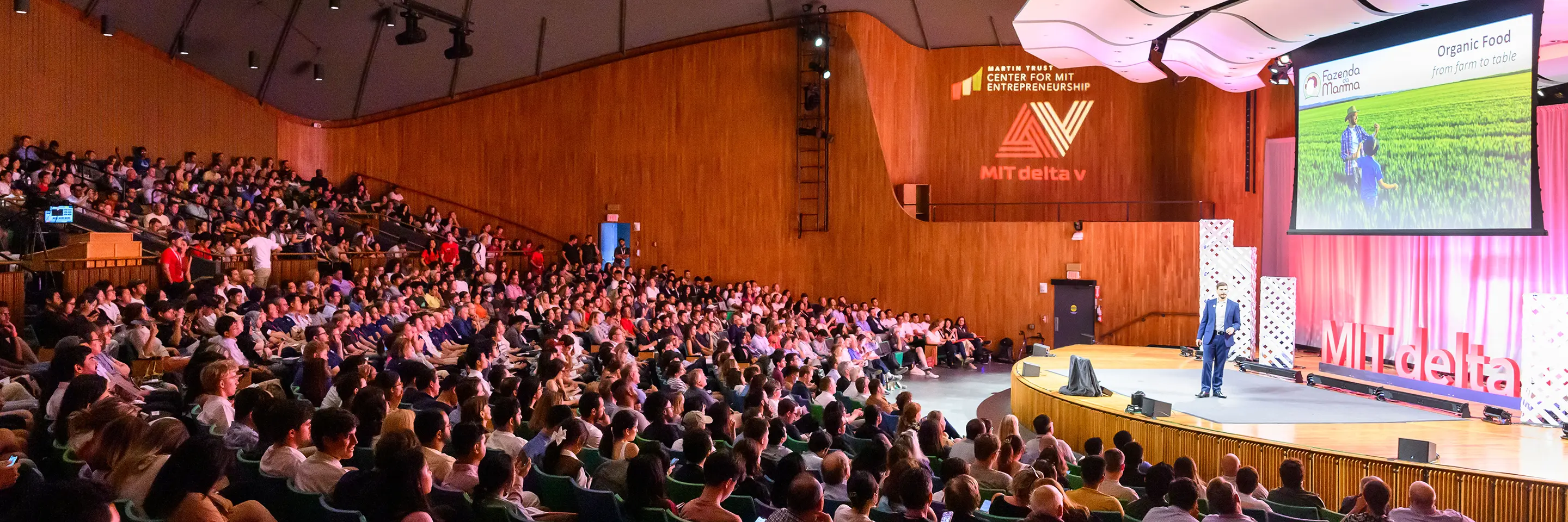 Crowded auditorium listens to presenter on stage