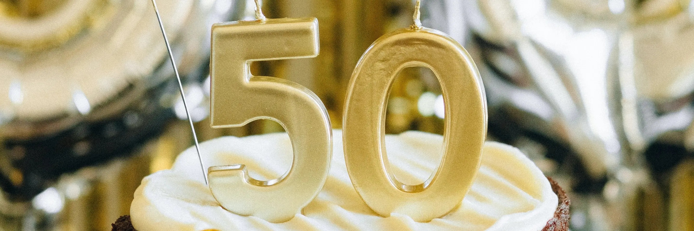 A chocolate cake on a stand with the number 50 on top of it