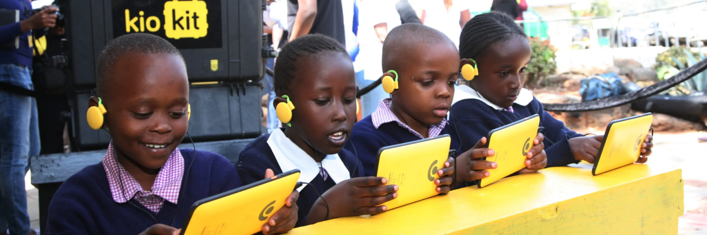 Children sitting in front of tablets smiling