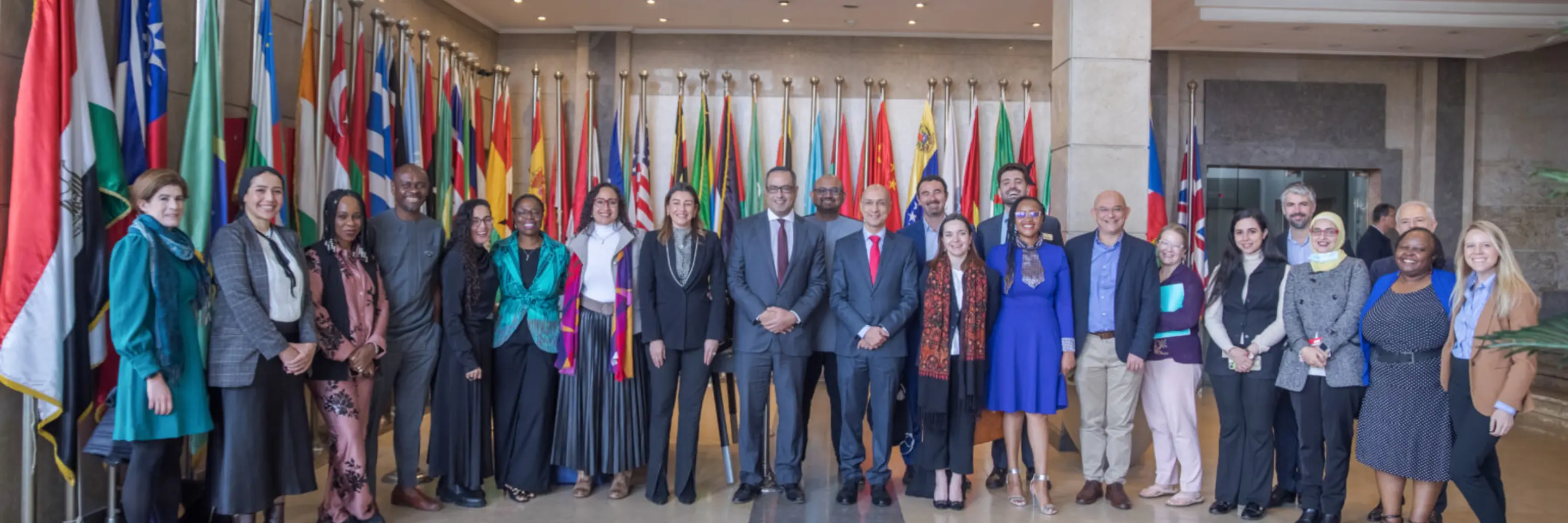 large group of entrepreneurs standing in official building in front of many flags