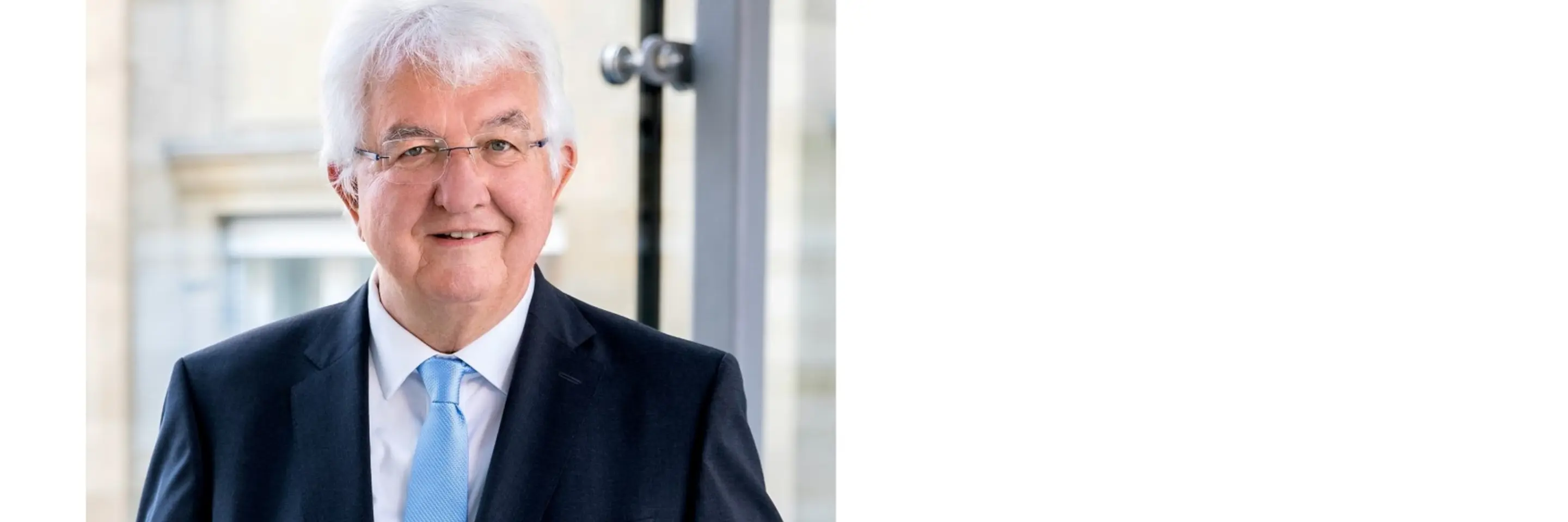 Robert Holzmann [older man with white hair, white skin and glasses wearing a dark suit with a light blue tie]