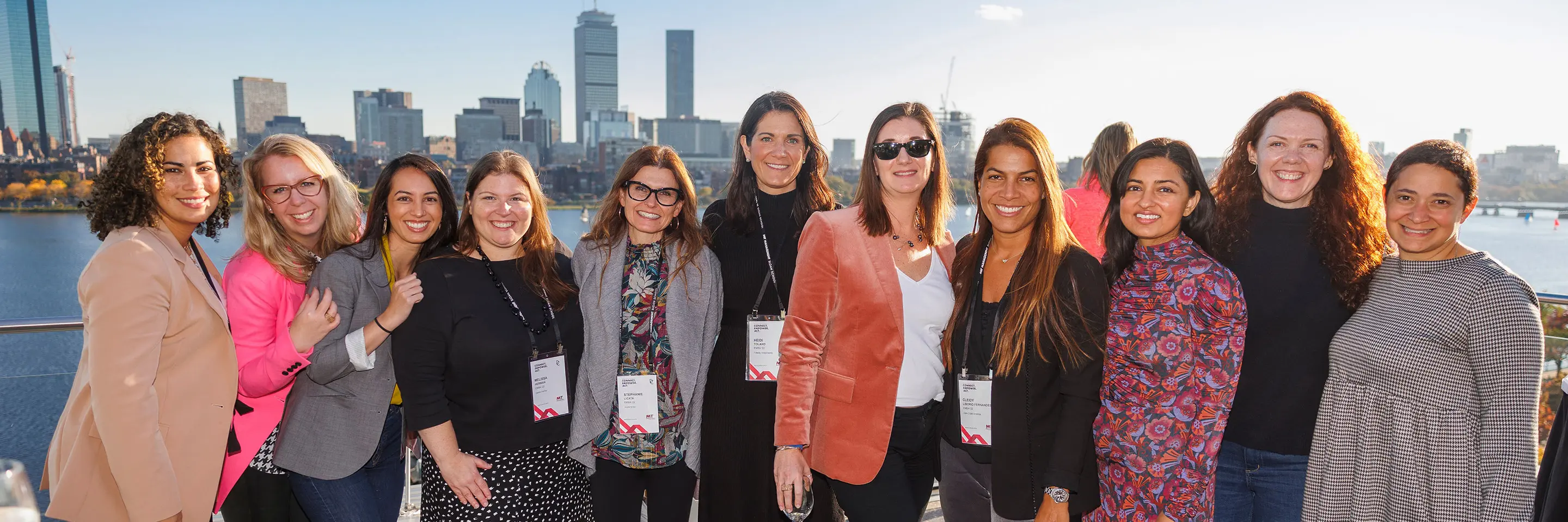Group of women pose for photo in front of Boston skyline