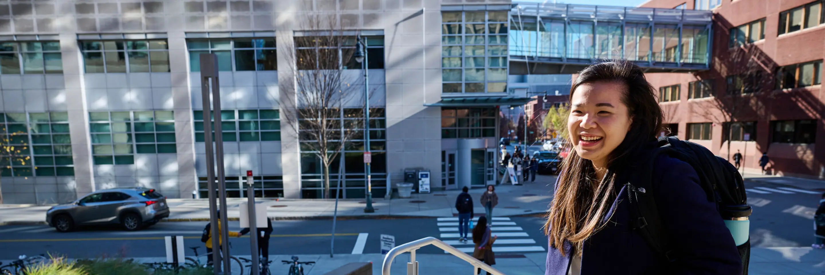 MBA Student Sharon Fan walking on MIT Sloan's campus on a sunny fall day.