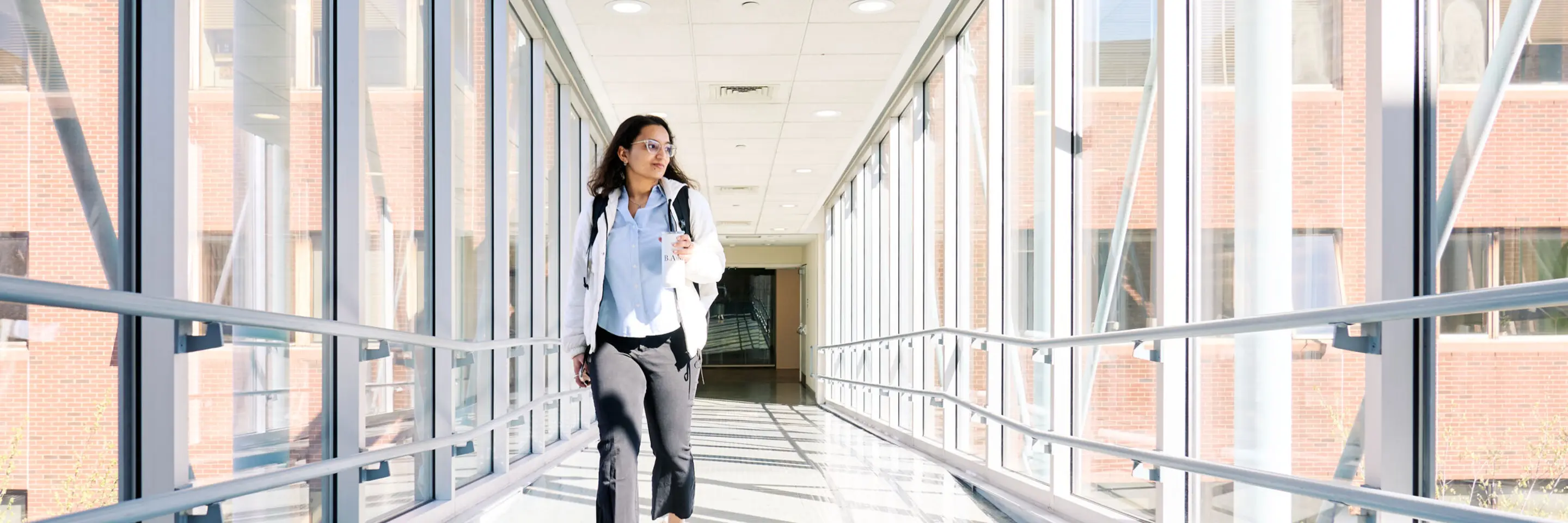 MBAn student Khushi Pathak walks across a skywalk between buildings