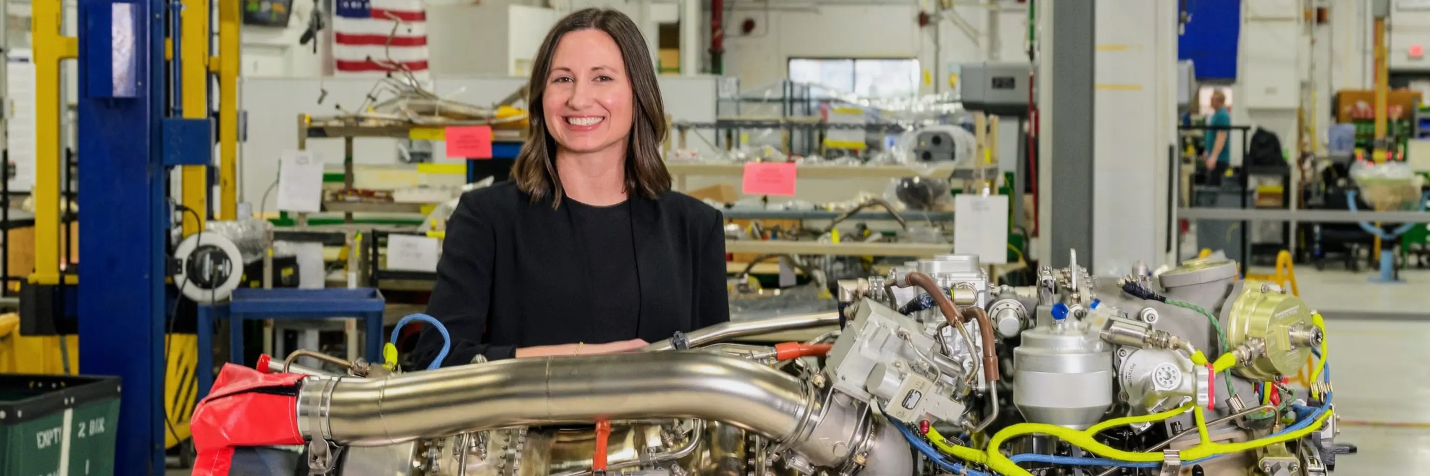 Sara Campbell EMBA '25 standing with a large engine in front of her