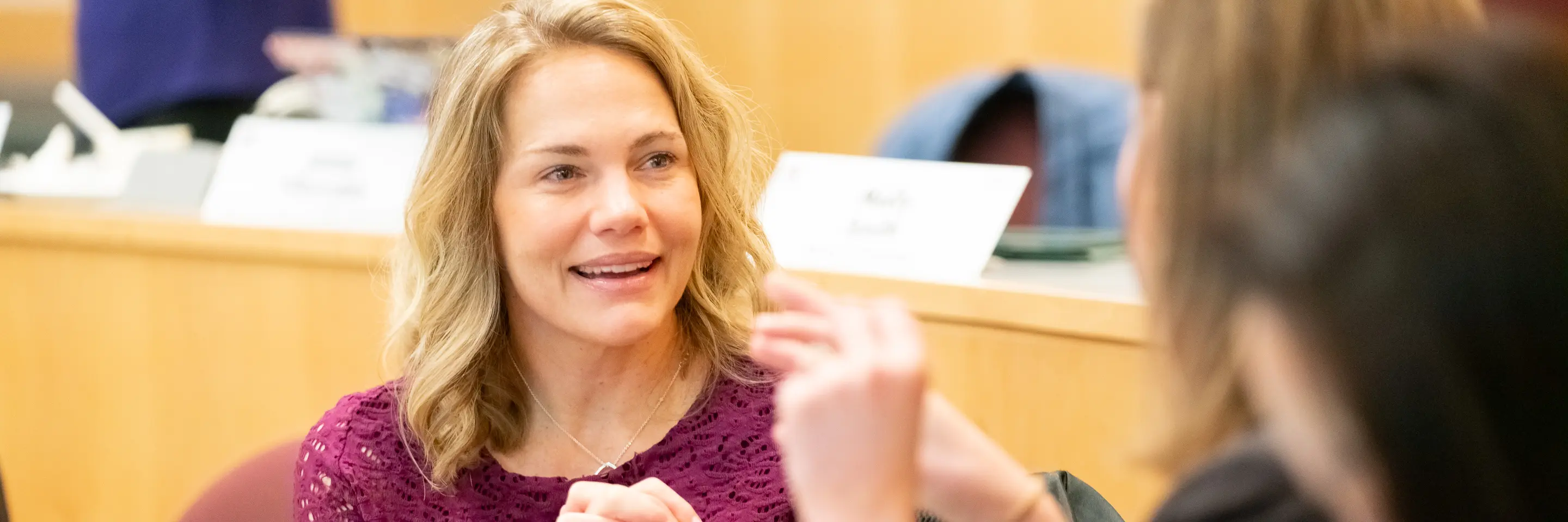 MJ Jamieson, EMBA '25, talking to a classmate, hands clasped.