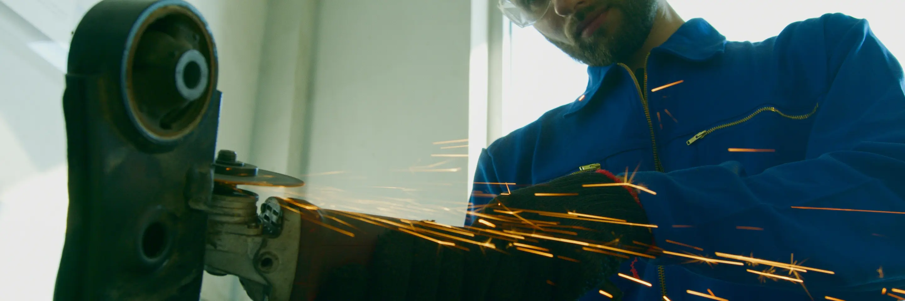A worker in goggles is using a grinding machine