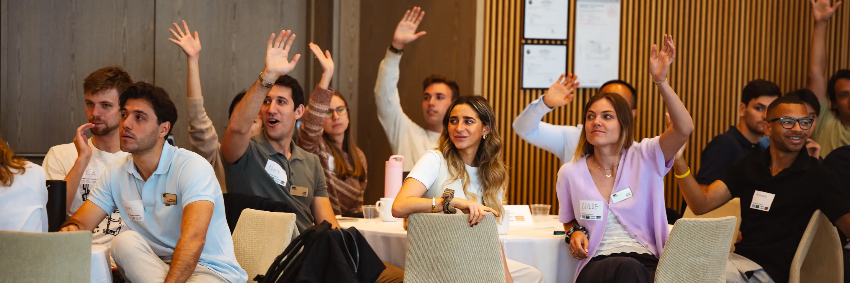 MIT MBA students raising their hands at an orientation program