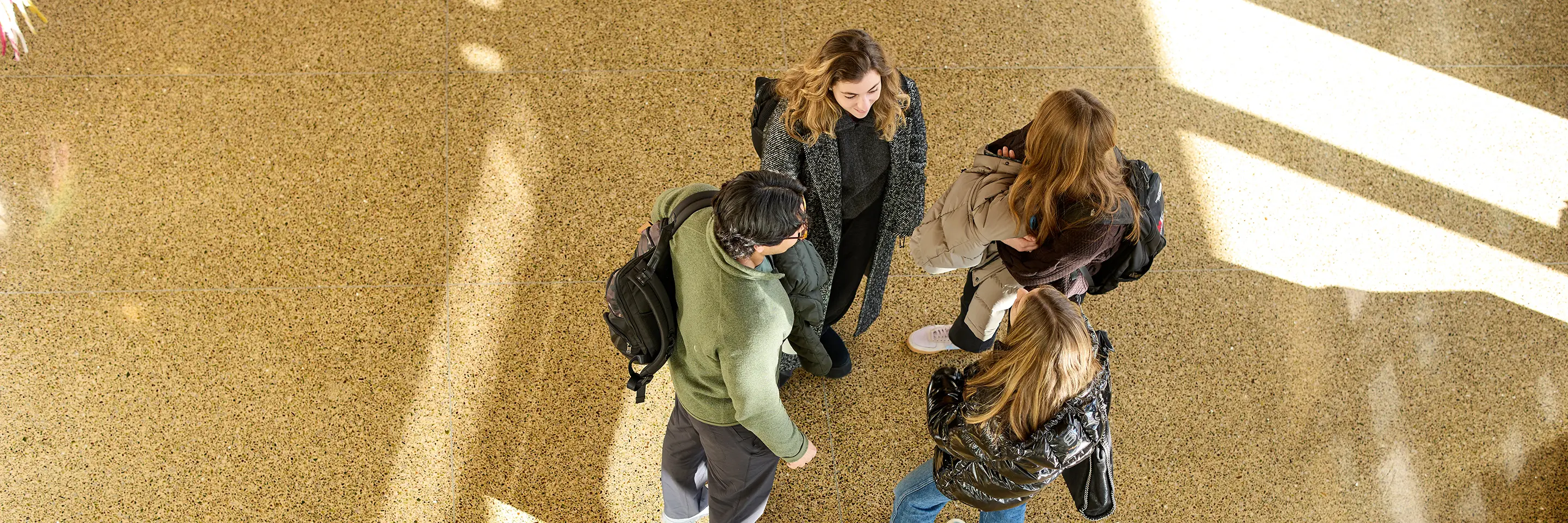 Four students stand together talking