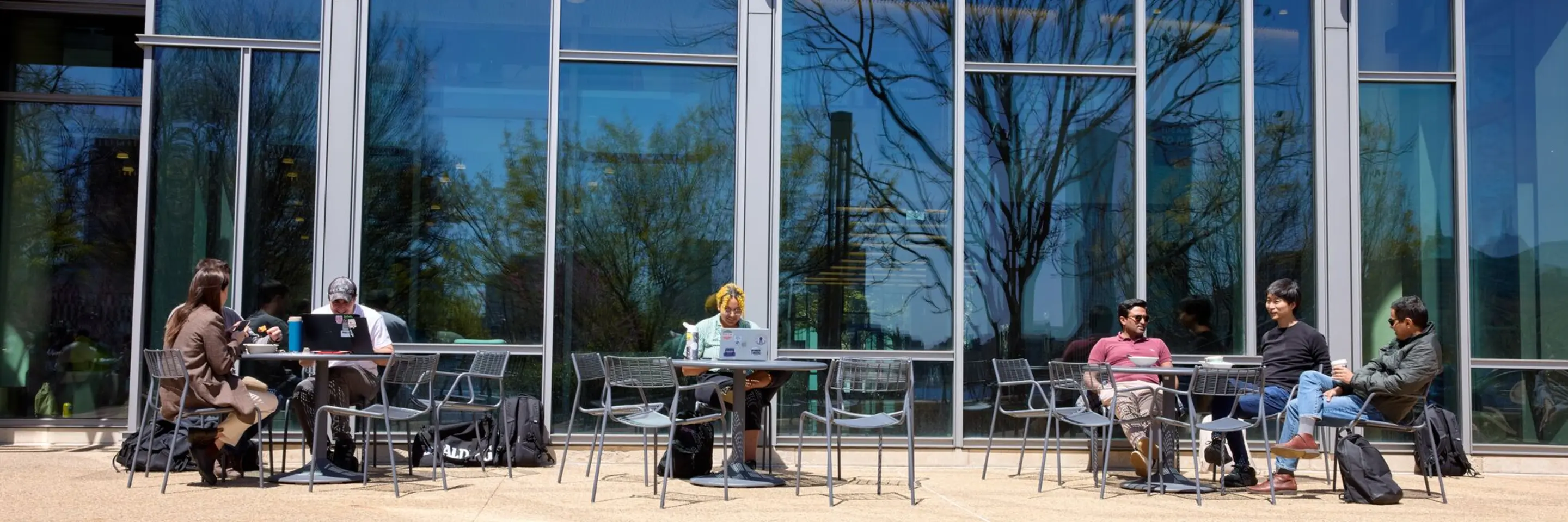 Students sitting at tables in front of the Memorial Drive entrance of E62