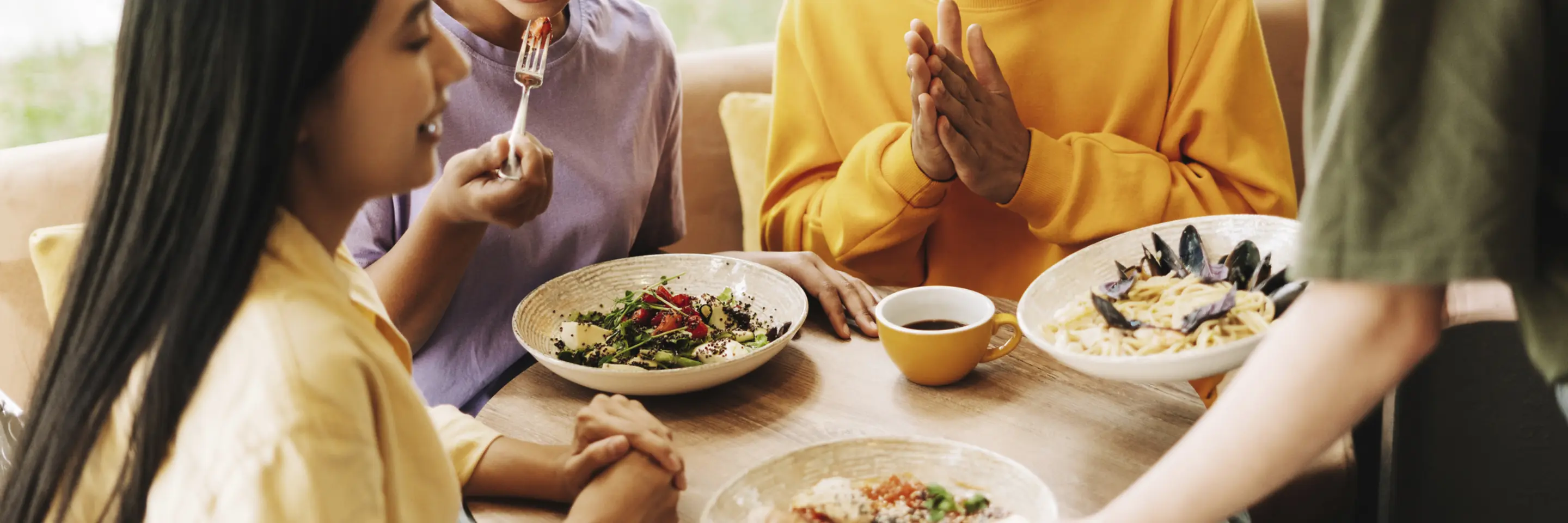 Waitress bringing food to a group of three friends in a restaurant.