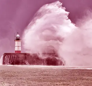 Huge waves crash over harbor sea wall and lighthouse
