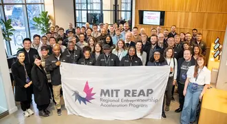 Group of people standing together holding a banner that says "Regional Entrepreneurship Acceleration Program