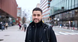 Mike Sanchez stands on a street in Cambridge and smiles at the camera