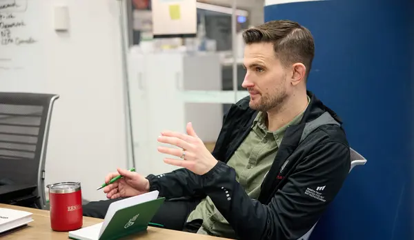 David Brown sits at a desk, talking to someone off camera. 