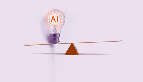 A lightbulb with the acronym 'AI' balances on a seesaw