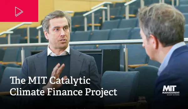 Florian Berg and Jay speak to each other in a large lecture hall. Berg's face is visible, while the camera looks over Jay's shoulder. White text reads: The MIT Catalytic Climate Finance Project. The MIT Sloan logo is visible in the bottom right hand corner 