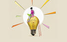 A person on a laptop sits on top of a lightbulb