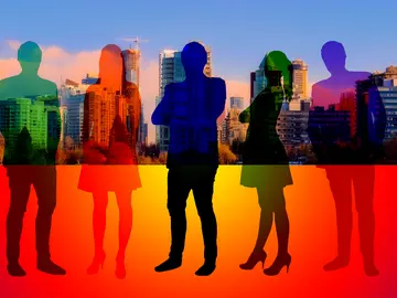 Silhouettes of business people in a rainbow of colors set to the backdrop of a city.