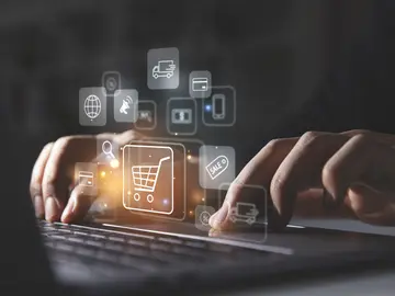 Young man using laptop with shopping cart icon