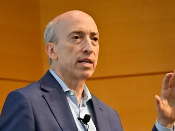 Man wearing business casual suit speaks before audience.
