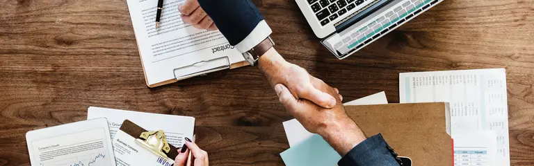 Men shaking hands over desk