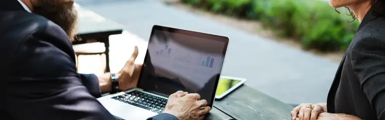 Man on laptop talking with a woman over table