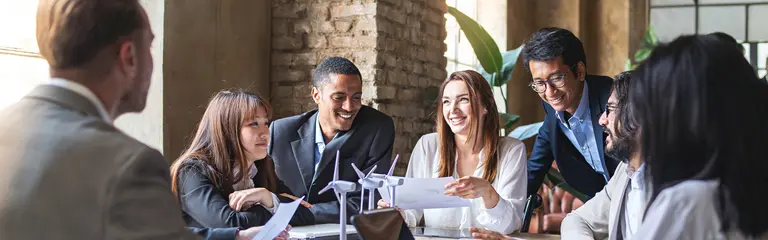 Group of people in corporate dress at a table, having a meeting