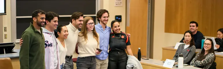 Group of students standing with arms around each other while someone outside the frame takes their photo