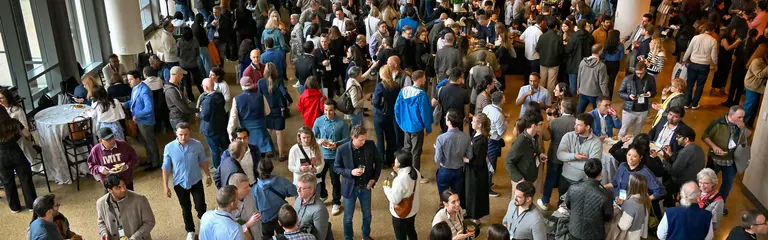 Large crowd of people gather together in open lobby of building