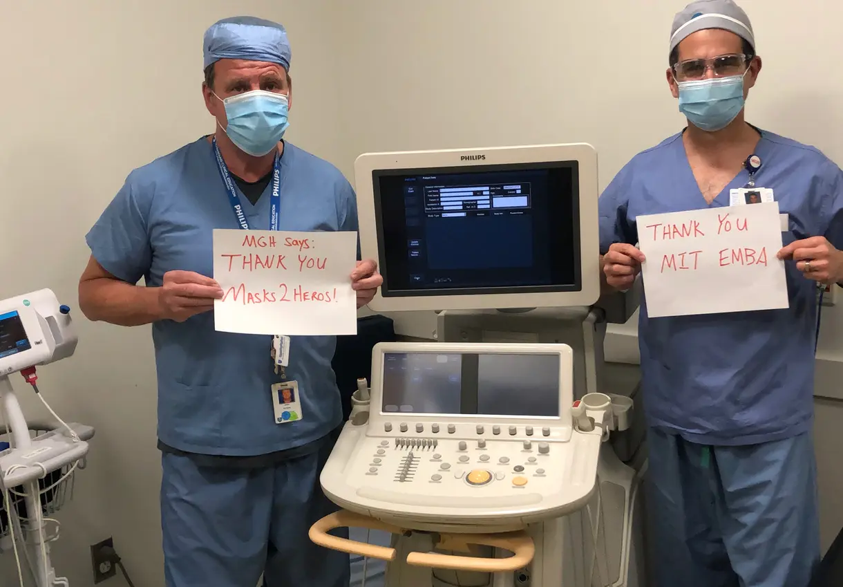Two healthcare workers with "thank you" signs to Masks 2 Heroes.
