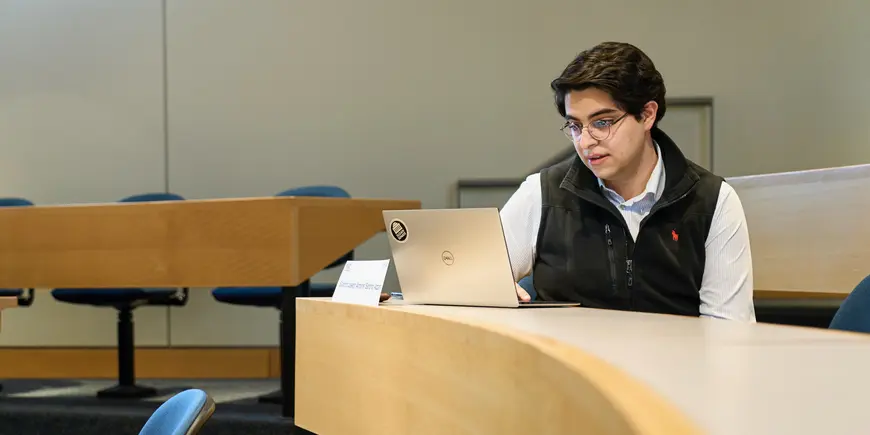 Sandro sitting in a classroom, looking at his laptop