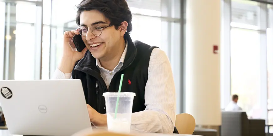 Sandro sitting in front of his laptop, speaking on the phone