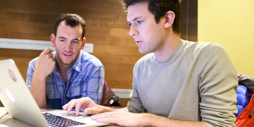 Jack O'Brien meets with another student as they look at a laptop.