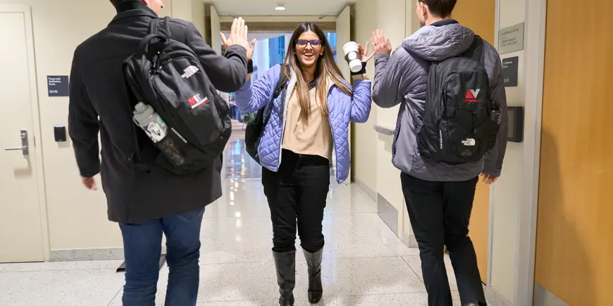 Jack O'Brien and another student high five their friend in the hallway.