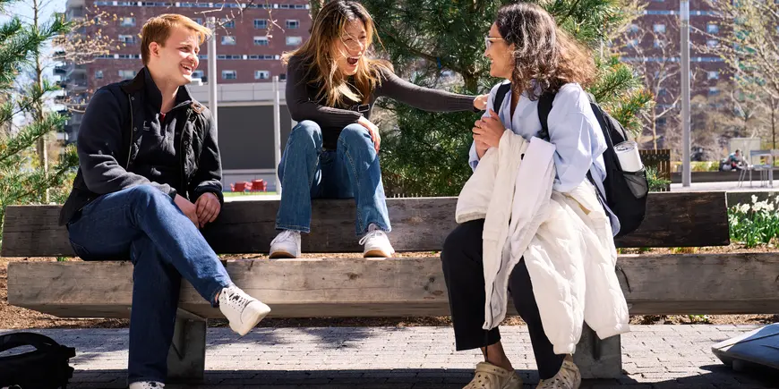 Khushi Pathak and her friends share a laugh outside while sitting on a bench.