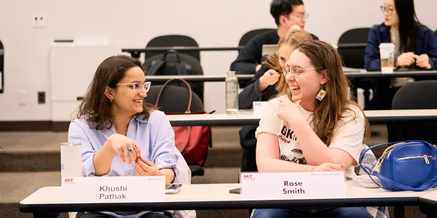 Khushi Pathak talks with her friend, Rose Smith, in a classroom.