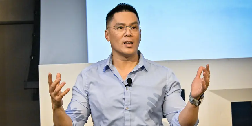 Man in a blue shirt addressing an audience.