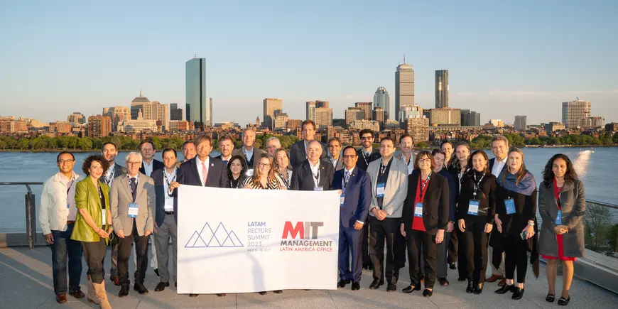 The first inaugural Latam Rectors Summit group stands in front of the Charles with the Boston skyline behind them.