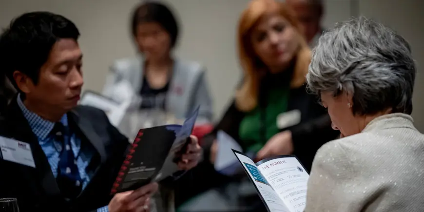 Attendees review programs at alumni event