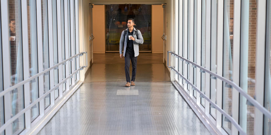 Abhi Rao carries a cup of coffee while walking to class