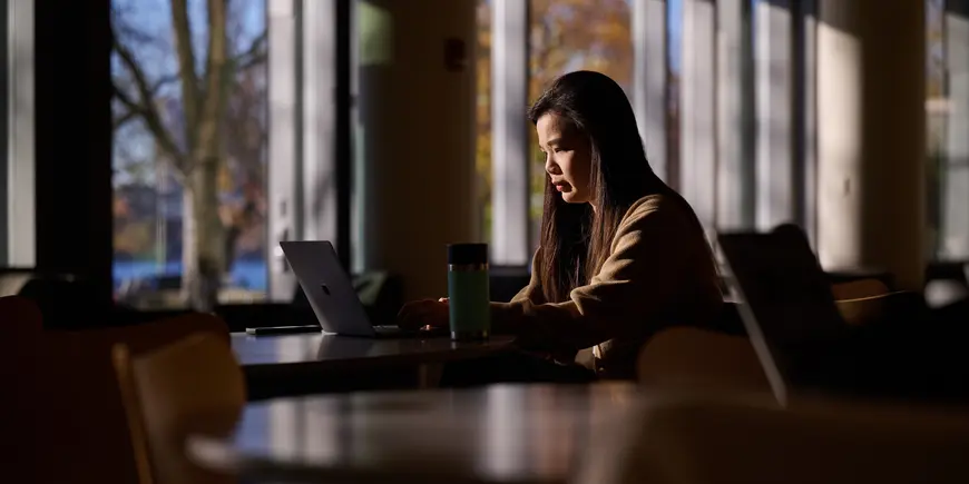 MBA student Sharon Fan sits in the MIT Sloan cafe checking her computer.