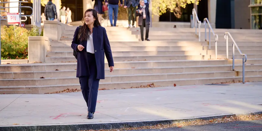 MBA student Sharon Fan walks away from the MIT Sloan buildings on a sunny fall day. 
