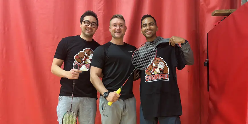 LGO student Abhi Rao holds a badminton racket and poses for a photo with two other badminton teammates