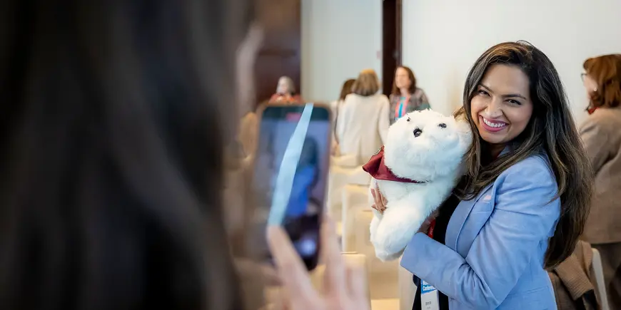 Smiling woman hugs white beaver plushie for photo