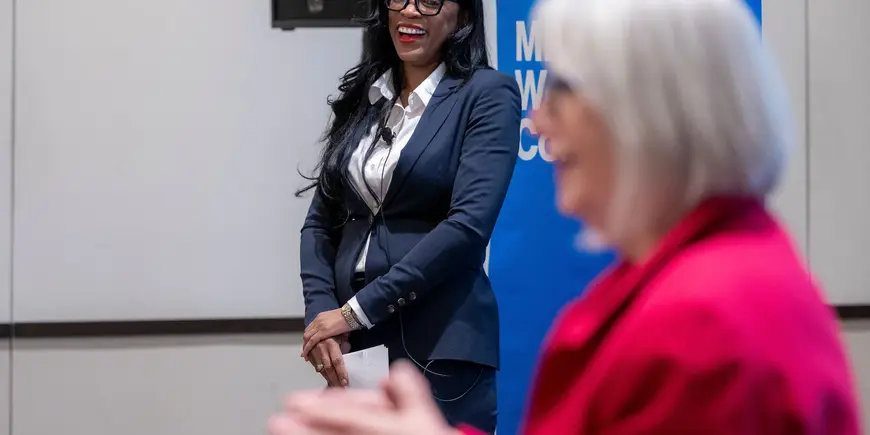 Woman smiles while listening to co-presenter at event