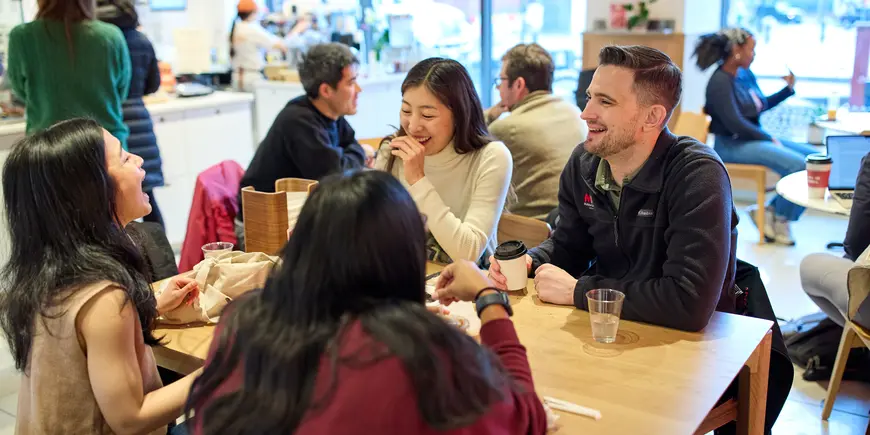 David Brown talks and laughs with four other people in a busy coffee shop
