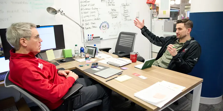 David Brown and Bill Aulet converse in an office. 