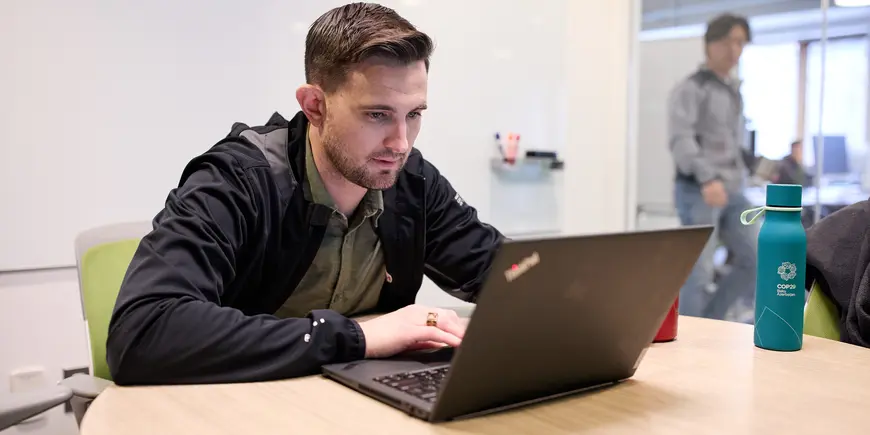 David Brown sits in front of a computer in a conference room. 