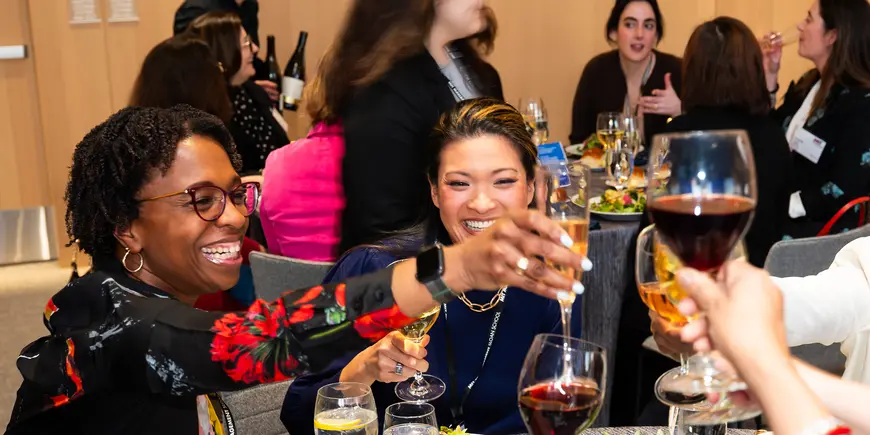 Group of smiling women raise their glasses in toast